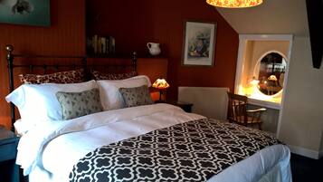 Una cama bien hecha con ropa de cama estampada, una mesita de noche con lámpara, una silla y una ventana con vistas al exterior.