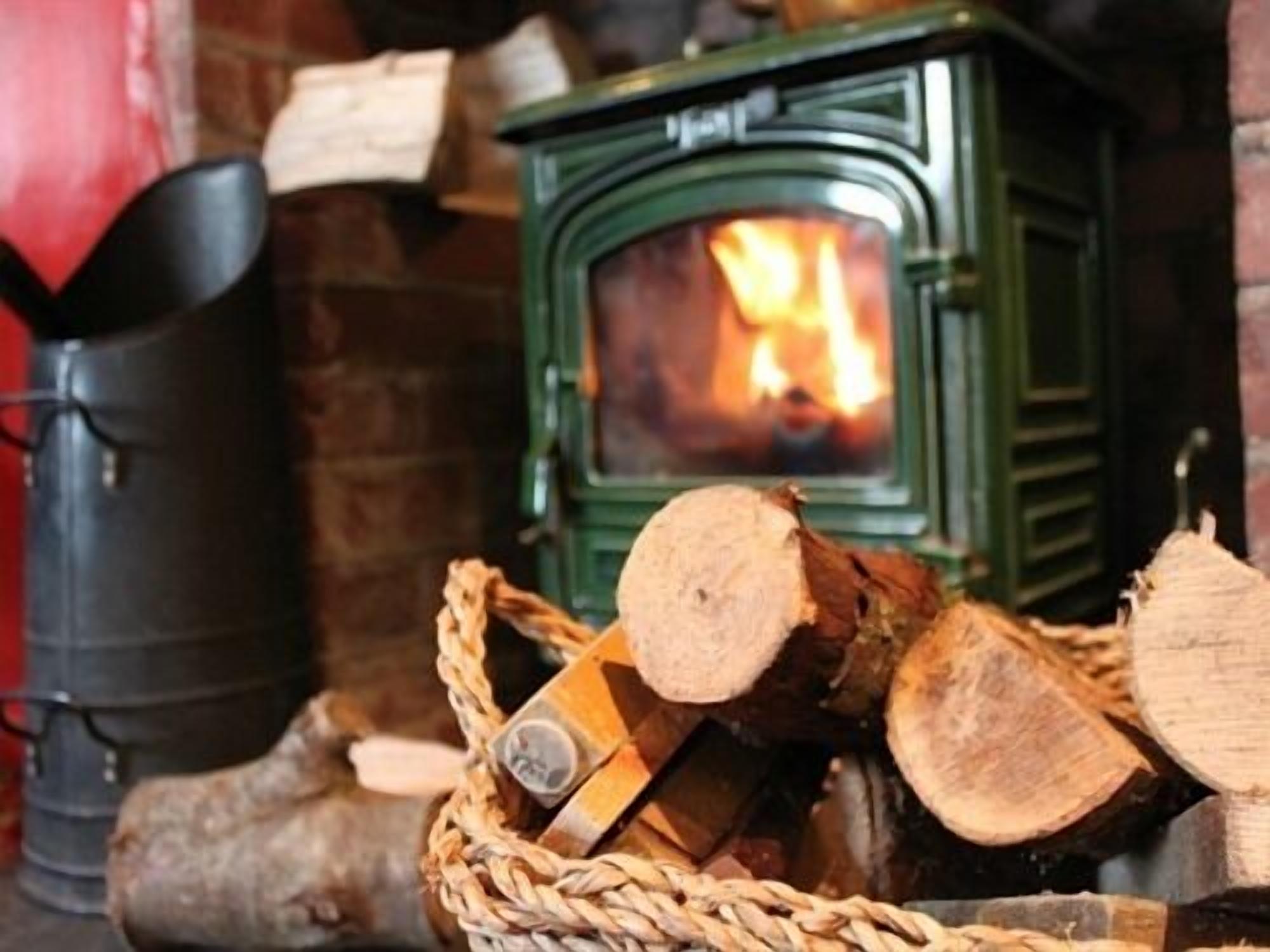 A fireplace with logs and a basket of firewood.