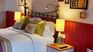 A bedroom with a bed, bedside tables, a nightstand, and wall decorations including framed pictures and a poster. - Lifton Hall (Lifton)
