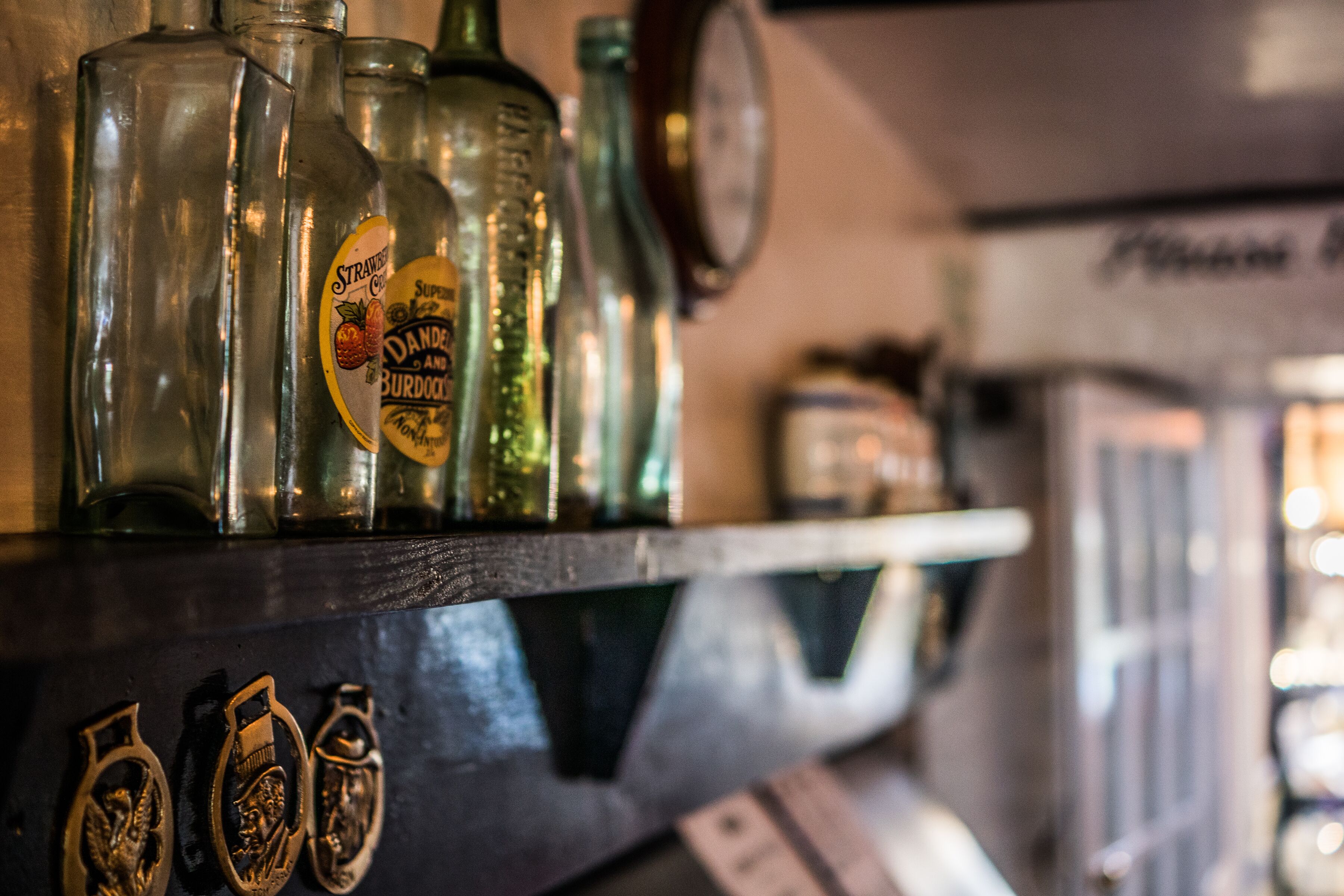 A shelf with vintage glass bottles and metal handles.
