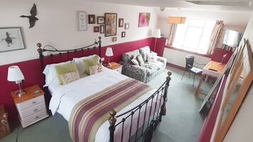 A bedroom with a bed, bedside tables, a chair, a desk, and a window.