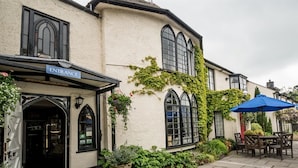 A building with an 'Entrance' sign, a covered outdoor seating area, and a paved courtyard. - Lifton Hall (Lifton)