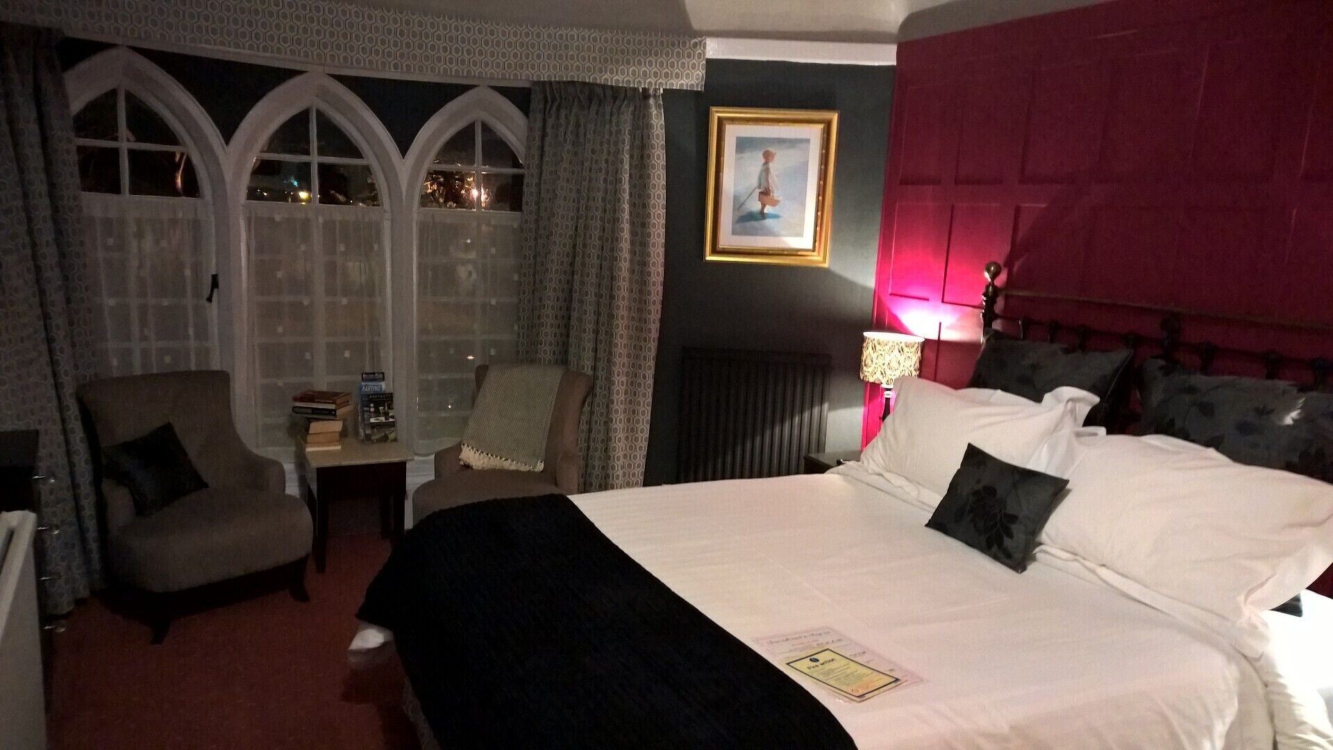 Una habitación de hotel con una cama grande, una silla, una mesita y una ventana con cortinas.