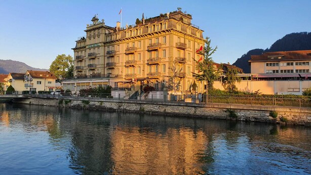 Un edificio histórico con múltiples balcones, fachada de piedra y reflejo en el agua.