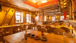 Un restaurante con interiores de madera, varias mesas de comedor y un amplio ventanal con vistas a la montaña.