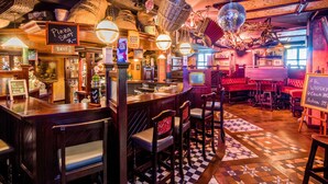 Zona de bar con mostradores de madera, taburetes y bolas de discoteca colgantes.