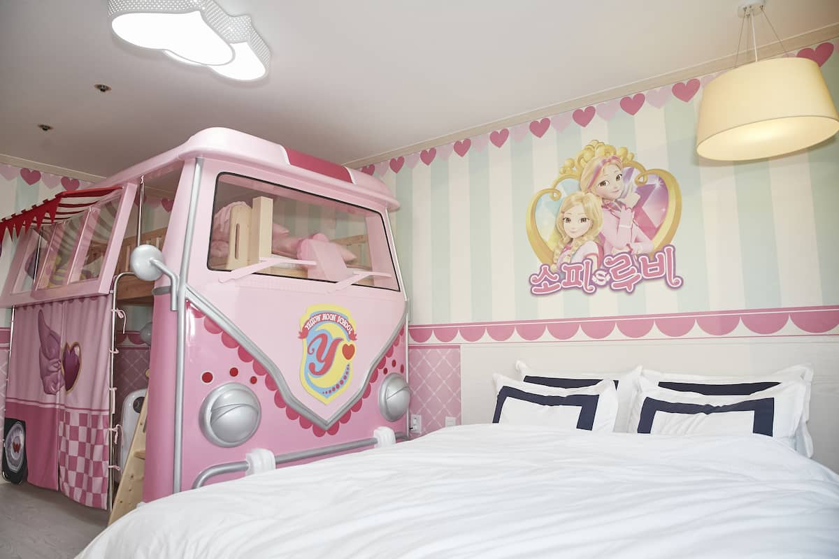 A pink-themed children's room with a bunk bed, a playhouse, and a wall with a cartoon character.