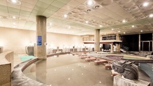 A large indoor swimming pool with a stone sculpture, a reception area, and a mezzanine level. - Hotel Miranda (Icheon)