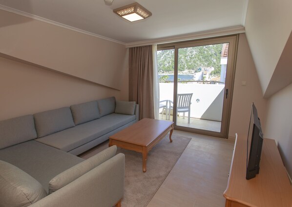 A modern living room with a grey sofa, a wooden coffee table, and a TV on a wooden stand.