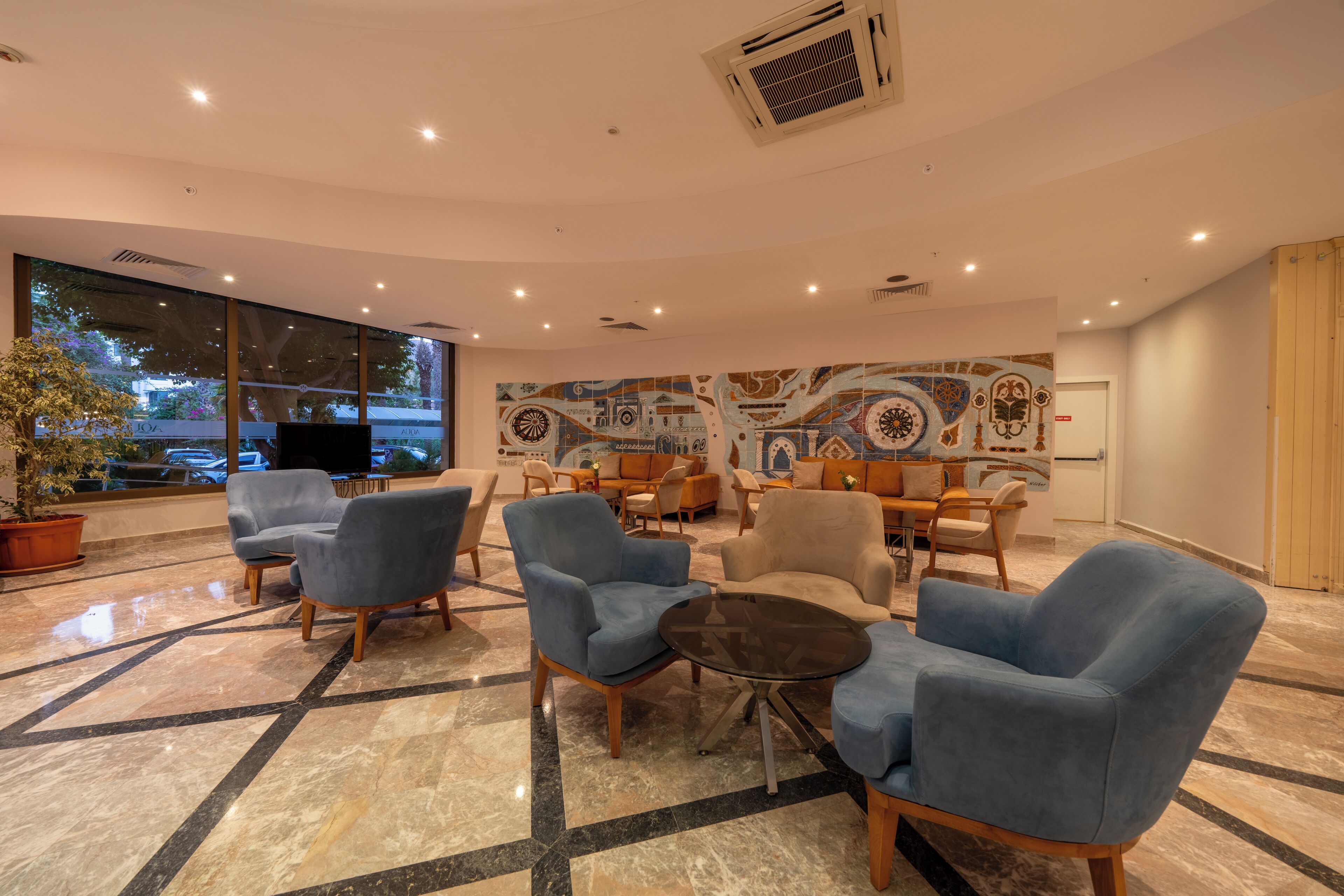 A modern lobby with a mix of seating options, a large window, and a decorative wall mural.