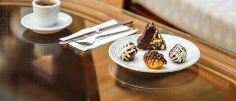 A glass table with a plate of assorted pastries and a cup of coffee.