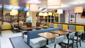 A restaurant with booths and tables, overhead lighting, and a mural on the wall. - Hampton Inn Madison Square Garden Area Hotel (New York)