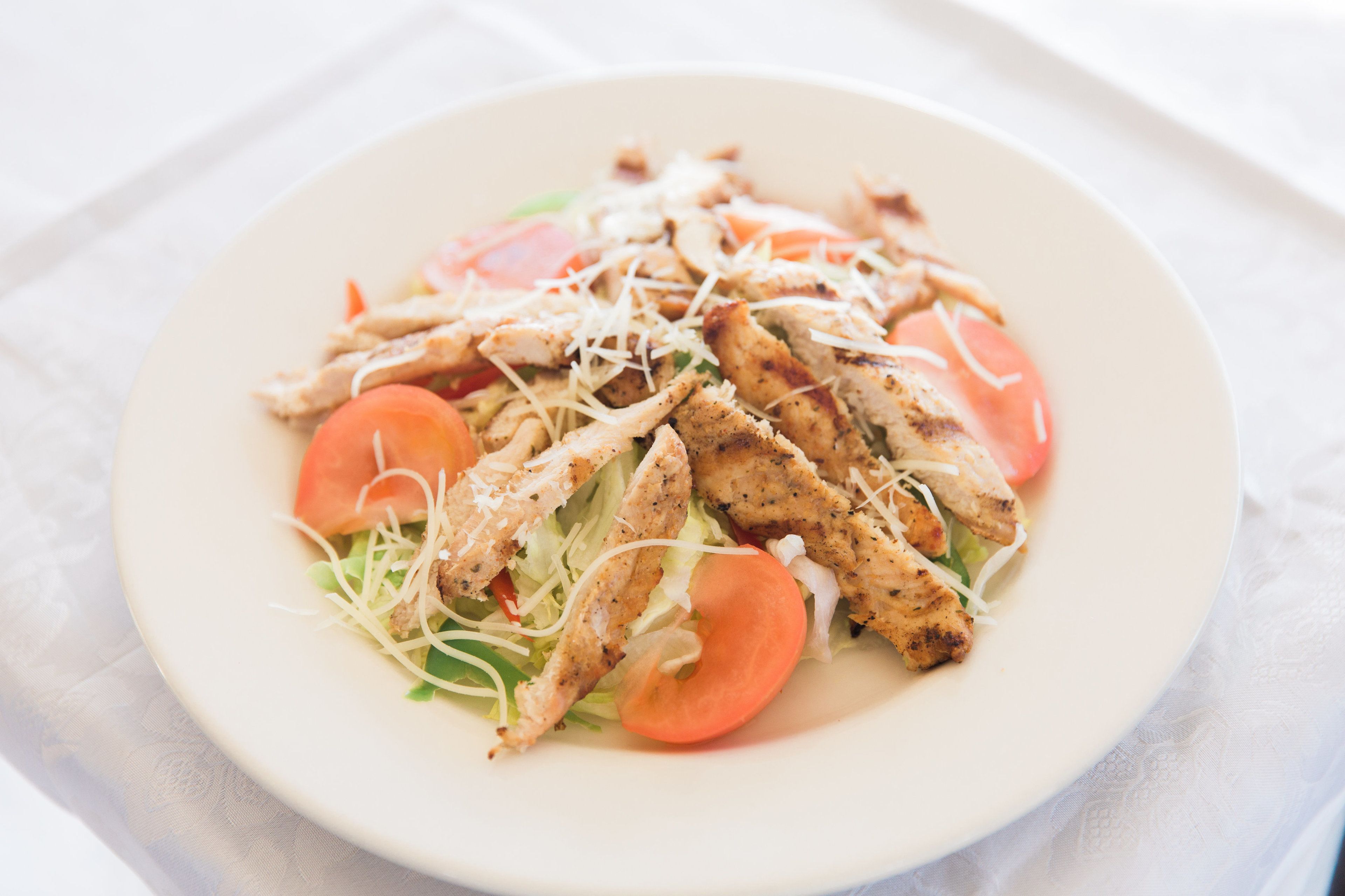Ensalada de pollo con lechuga, tomates y queso rallado.