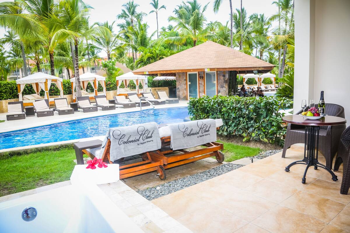A poolside area with lounge chairs, a hot tub, and a covered seating area.