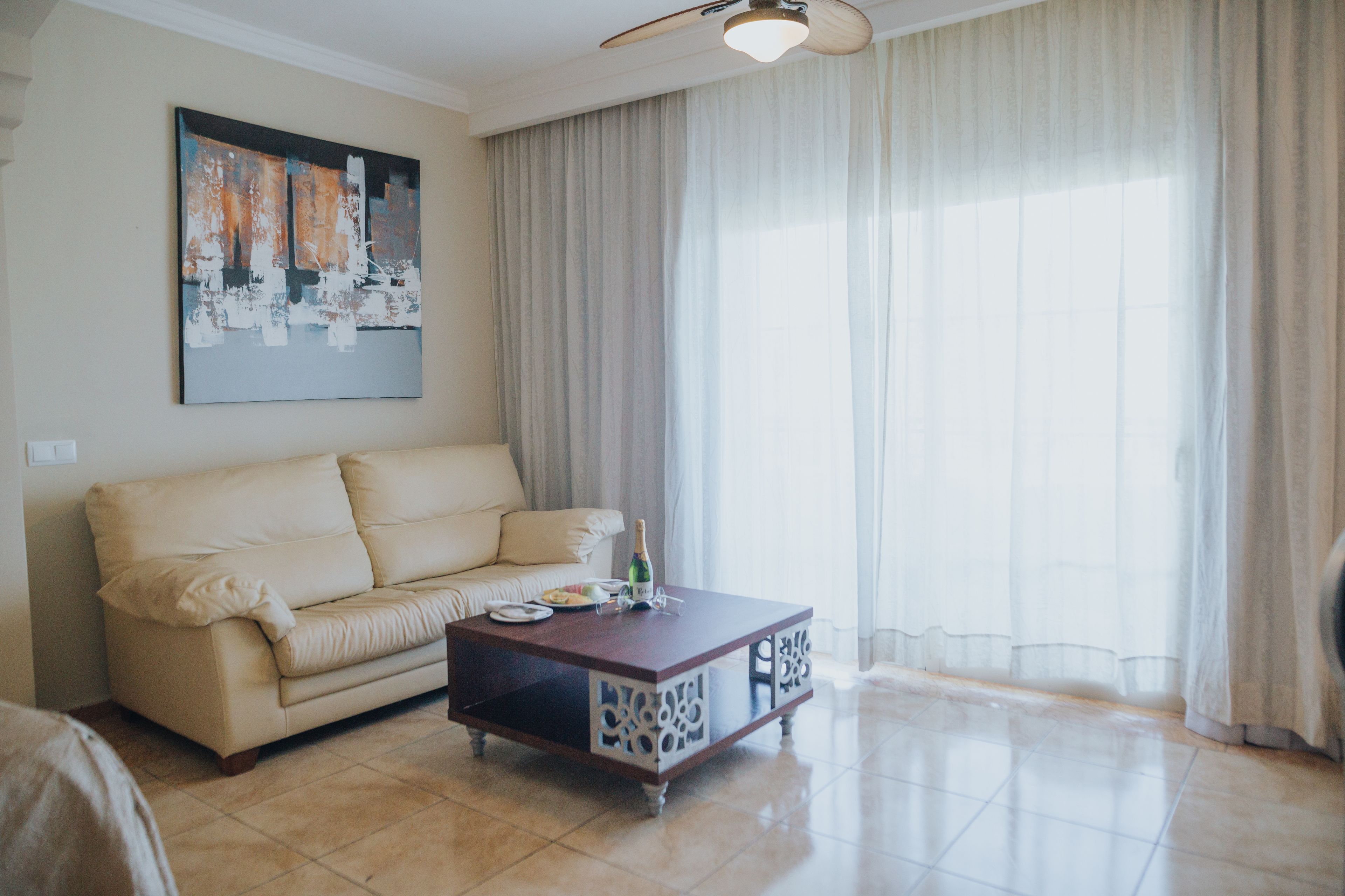 Una sala de estar con un sofá color beige, una mesa de centro de madera y un cuadro en la pared.