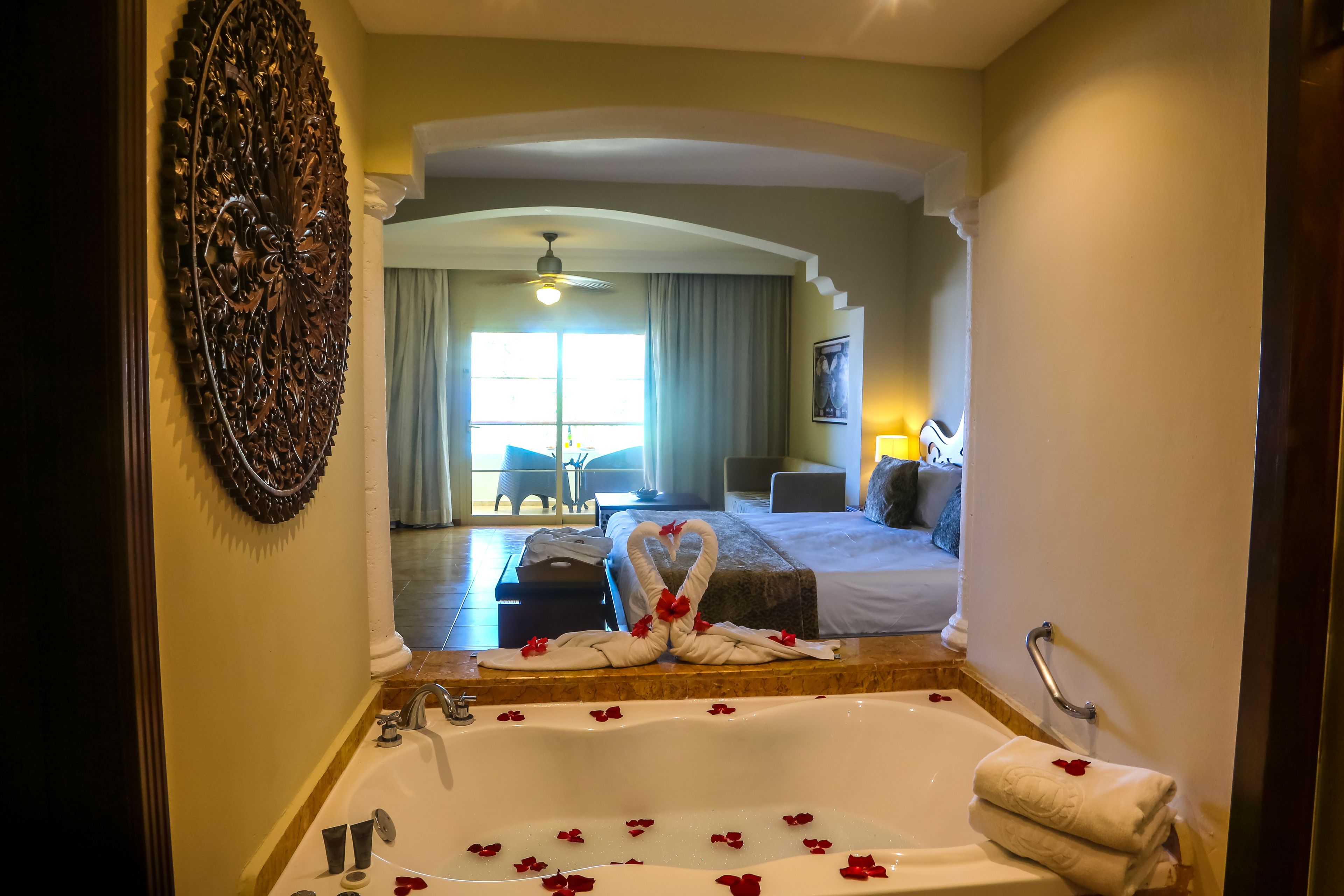 A hotel bathroom with a large bathtub, a shower, and a sink. There is a towel rack and a decorative wall piece.