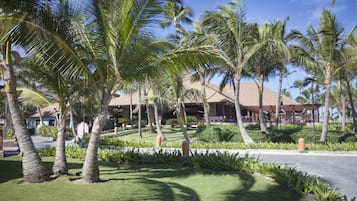 Een resort met palmbomen, een overdekt buitengebied en een verzorgd gazon.