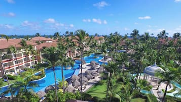 Un resort con varias piscinas, palmeras y vista al océano.