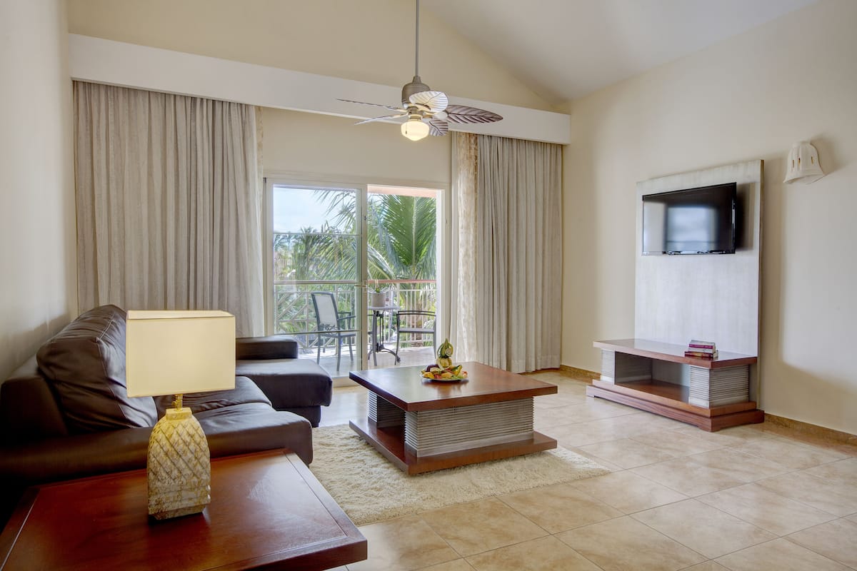 A modern living room with a sofa, coffee table, TV, and a ceiling fan.