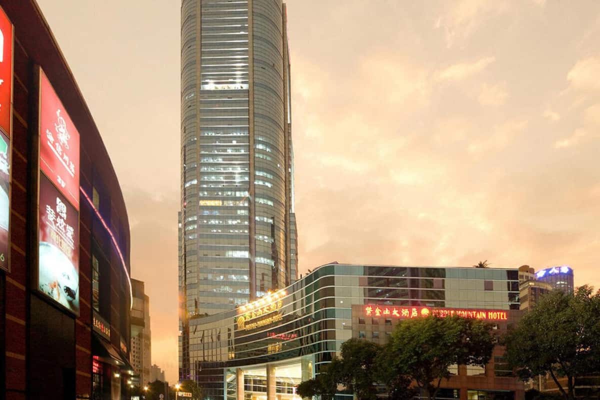 Un edificio hotelero alto y moderno con fachada curva y señalización iluminada.