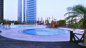 A rooftop pool area with lounge chairs and a wooden deck. - Jinling Purple Mountain Hotel Shanghai (Shanghai)