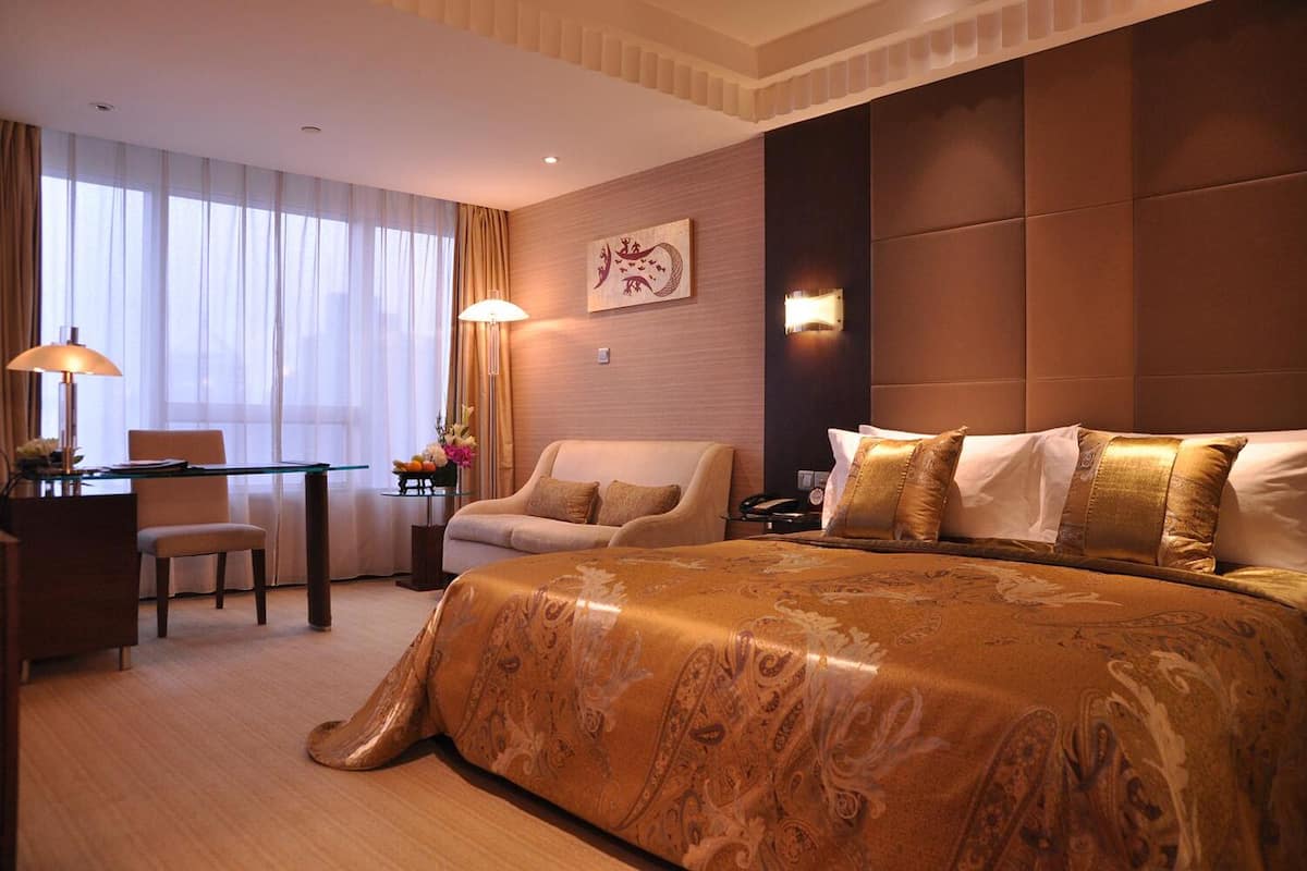 Habitación de hotel con una cama grande, un escritorio, una silla y un sofá.