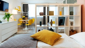 A hotel room with a bed, a desk, a chair, a bookshelf, and a television. - Hotel Corel (The Hague)
