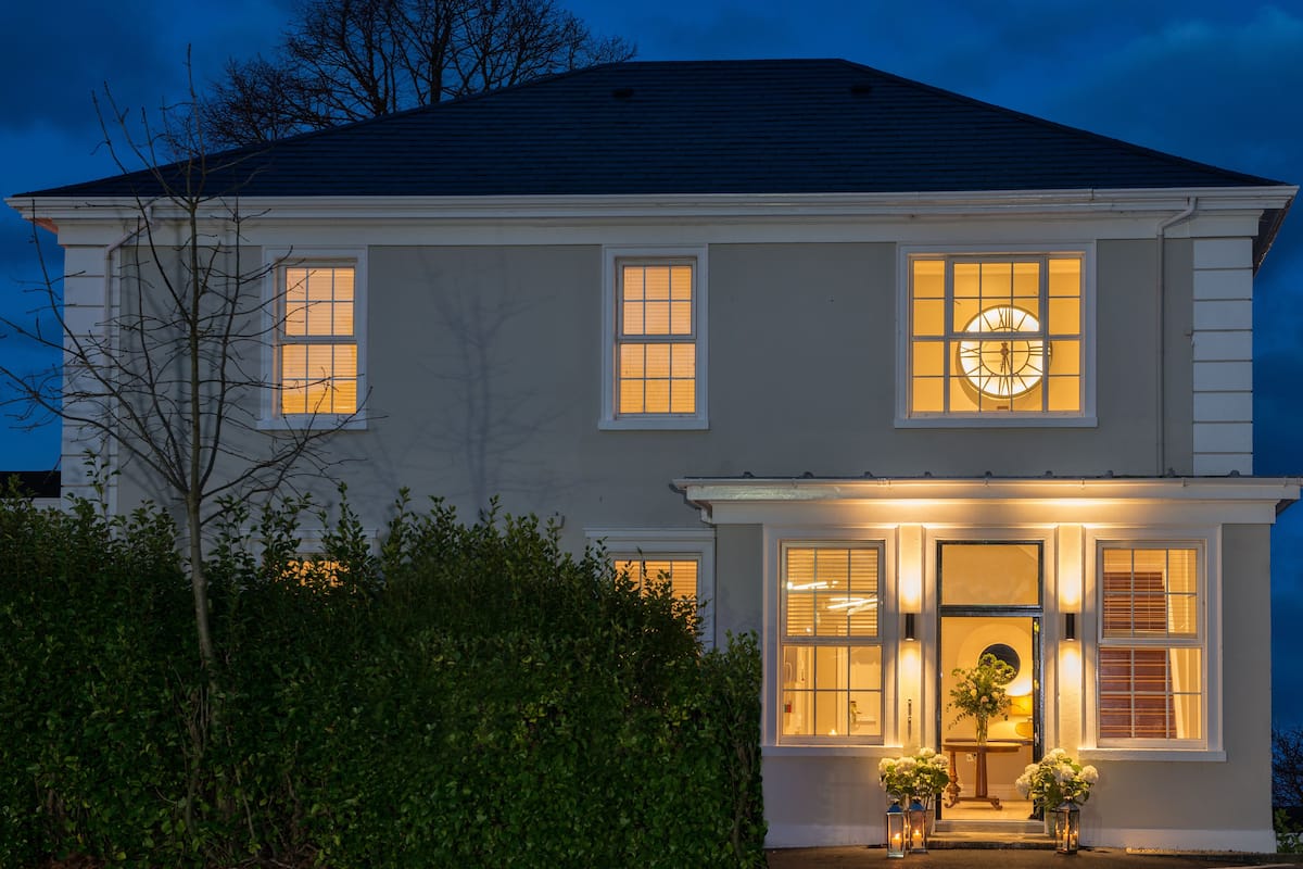 A two-story house with a front porch, large windows, and a clock on the second floor.