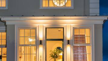A two-story house with a well-lit entrance, large windows, and a clock above the door.