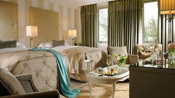 A hotel room with two beds, a sitting area with a table, and a view of the outdoors.