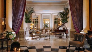 Een ruime lobby met een piano, comfortabele zitplaatsen en grote ramen.
