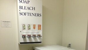 A laundry room with a sign for soap, bleach, and softeners, a coin-operated dryer, and a wall-mounted dispenser. - Alaska's Select Inn Wasilla (Wasilla)