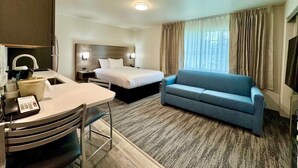 A hotel room with a bed, a sofa, a desk with a telephone, and a window with curtains. - Alaska's Select Inn Wasilla (Wasilla)