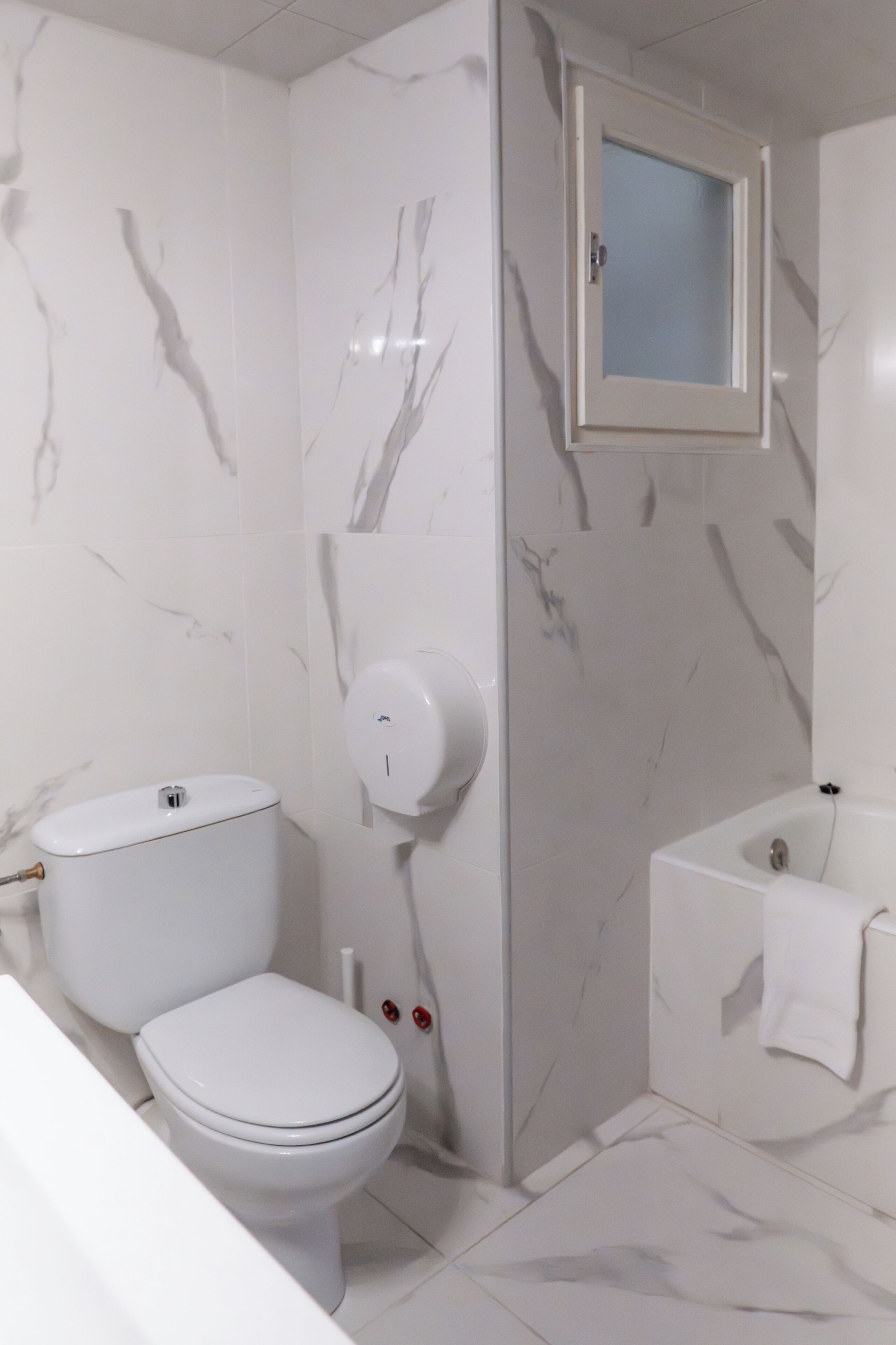 A bathroom with a toilet, a hand dryer, a sink, and a mirror.
