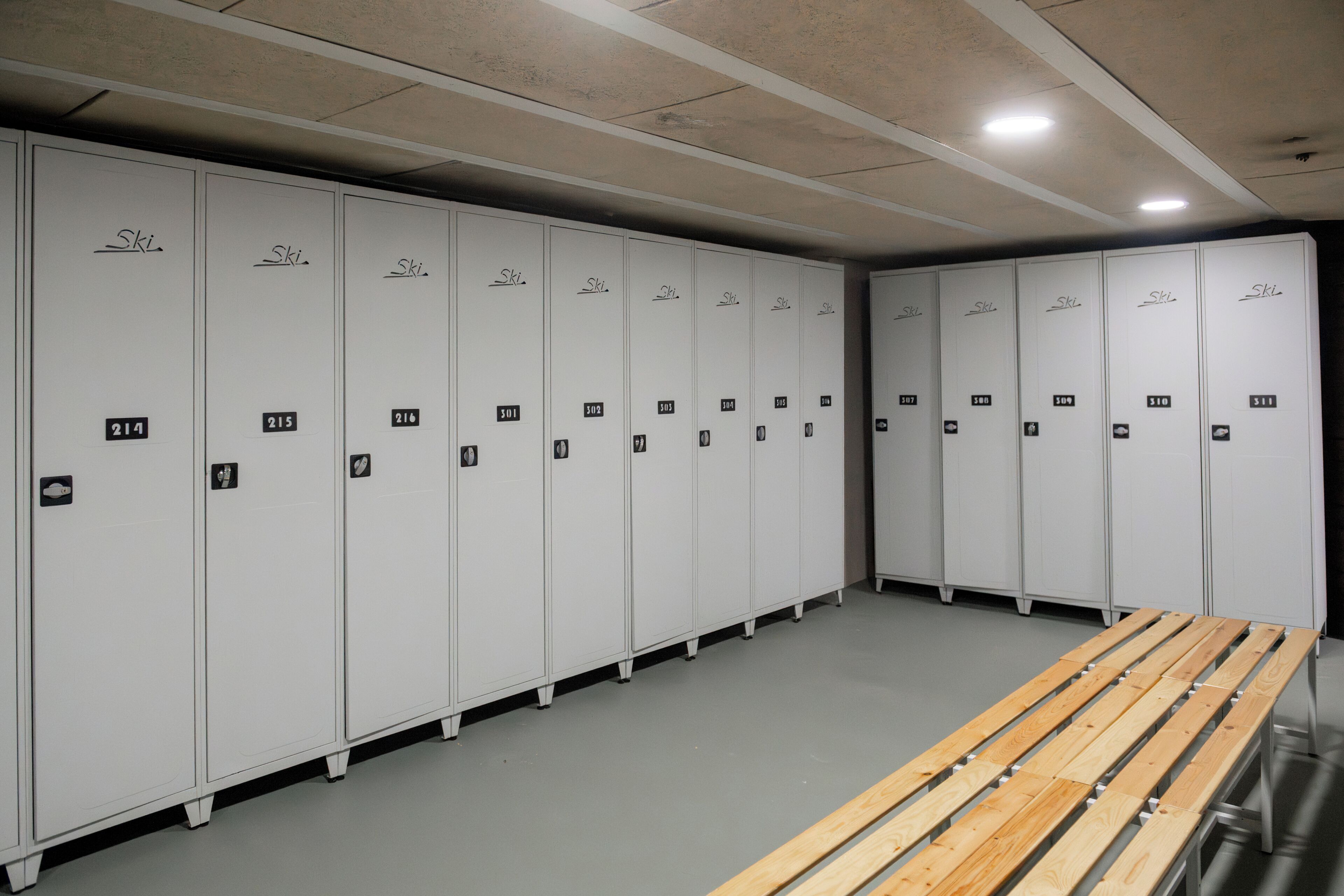 Een rij witte kluisjes, waarvan er 'Ski' op staat, genummerd van 214 tot 511, en een houten bank in het midden.
