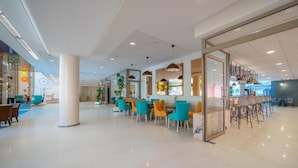 A spacious lobby with modern furniture, a glass wall, and a bar area. - Blaumar (Blanes)
