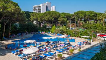 A pool area with multiple swimming pools, lounge chairs, and umbrellas.