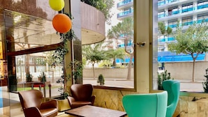 Un interior moderno con asientos, una mesa y ventanas amplias que ofrecen vistas al exterior.