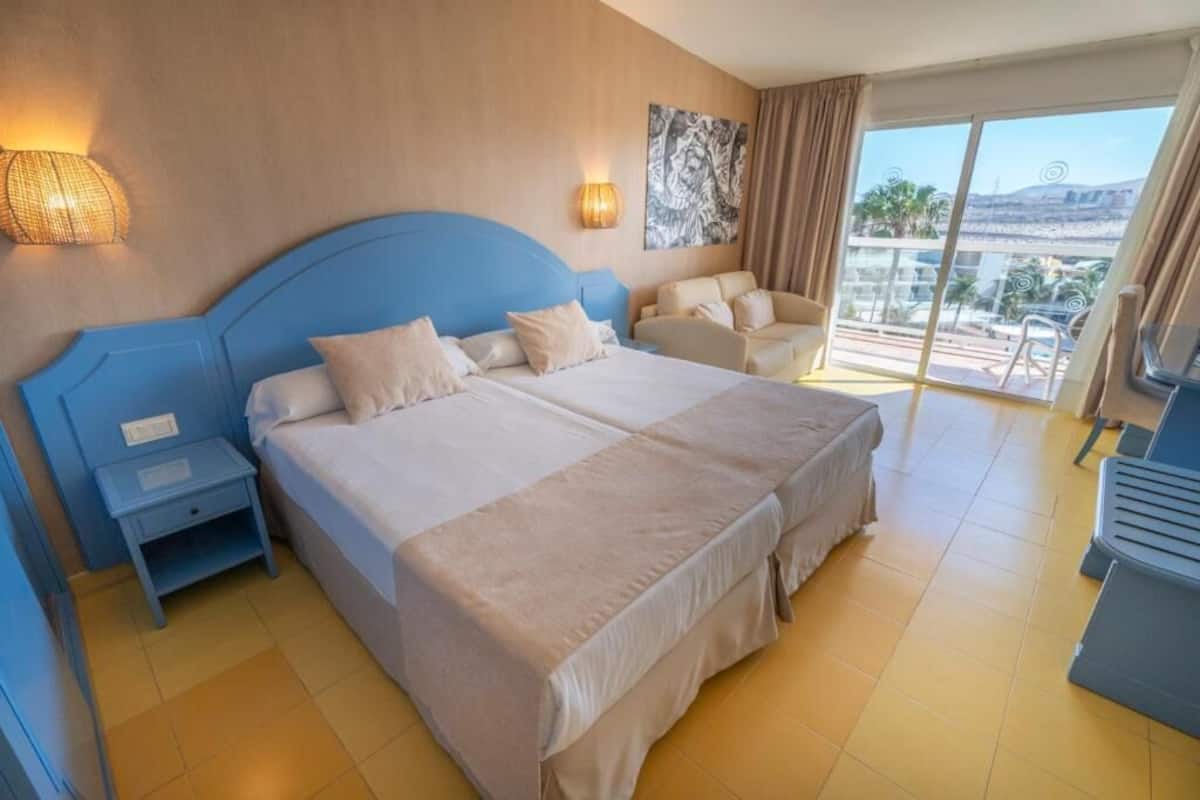 Ett hotellrum med en stor säng, en soffa, ett skrivbord och en balkong med utsikt.