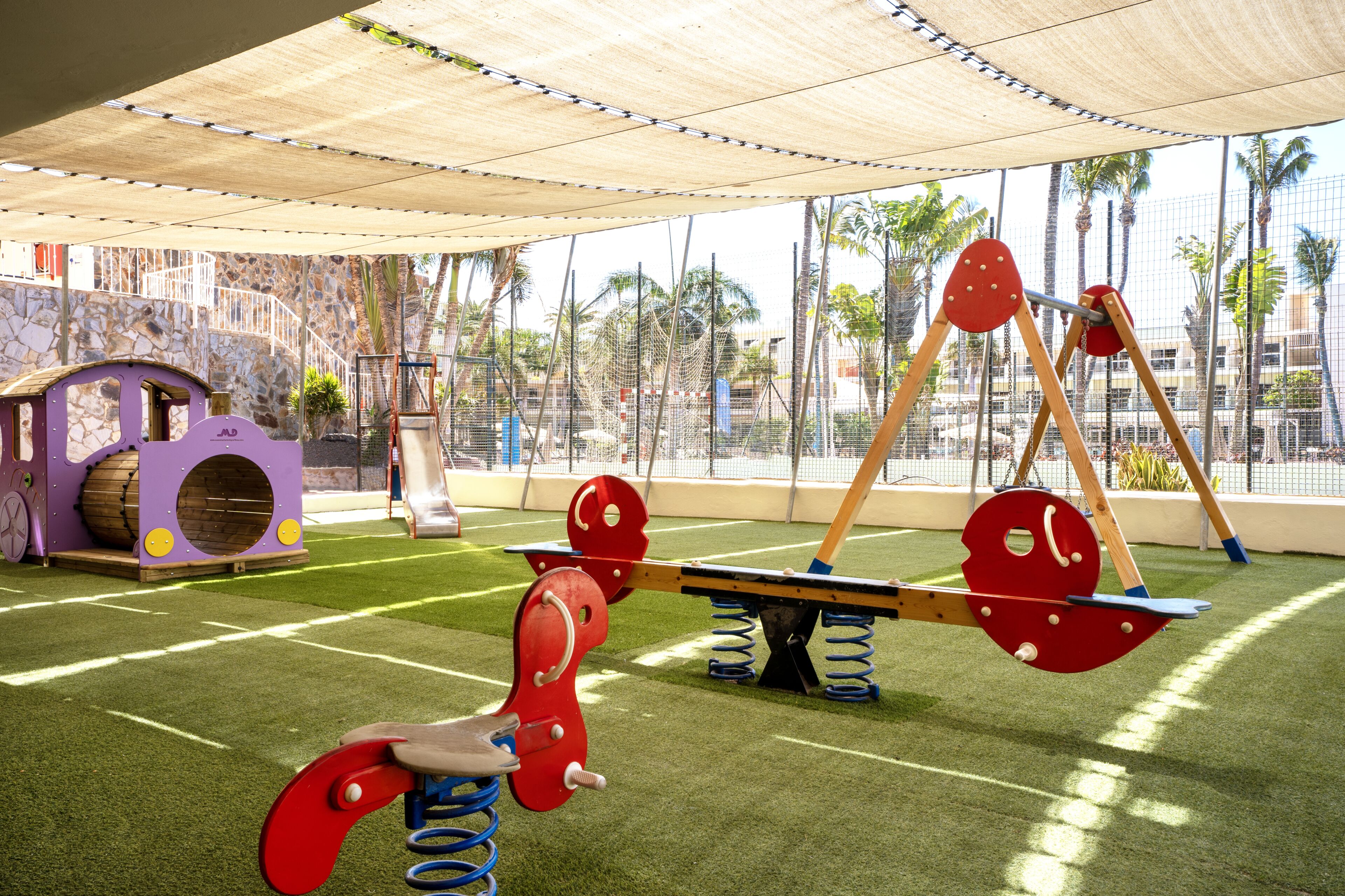 Un parque infantil con un sube y baja, una estructura para escalar y un tobogán.