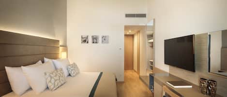 A modern hotel room with a large bed, a desk, a flat-screen TV, and a wardrobe.