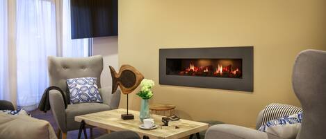 Una sala moderna con chimenea, asientos cómodos y un televisor de pantalla plana.