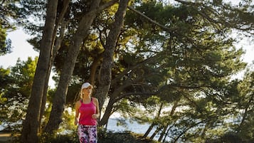 A person jogging in a wooded area with trees and a body of water in the background.