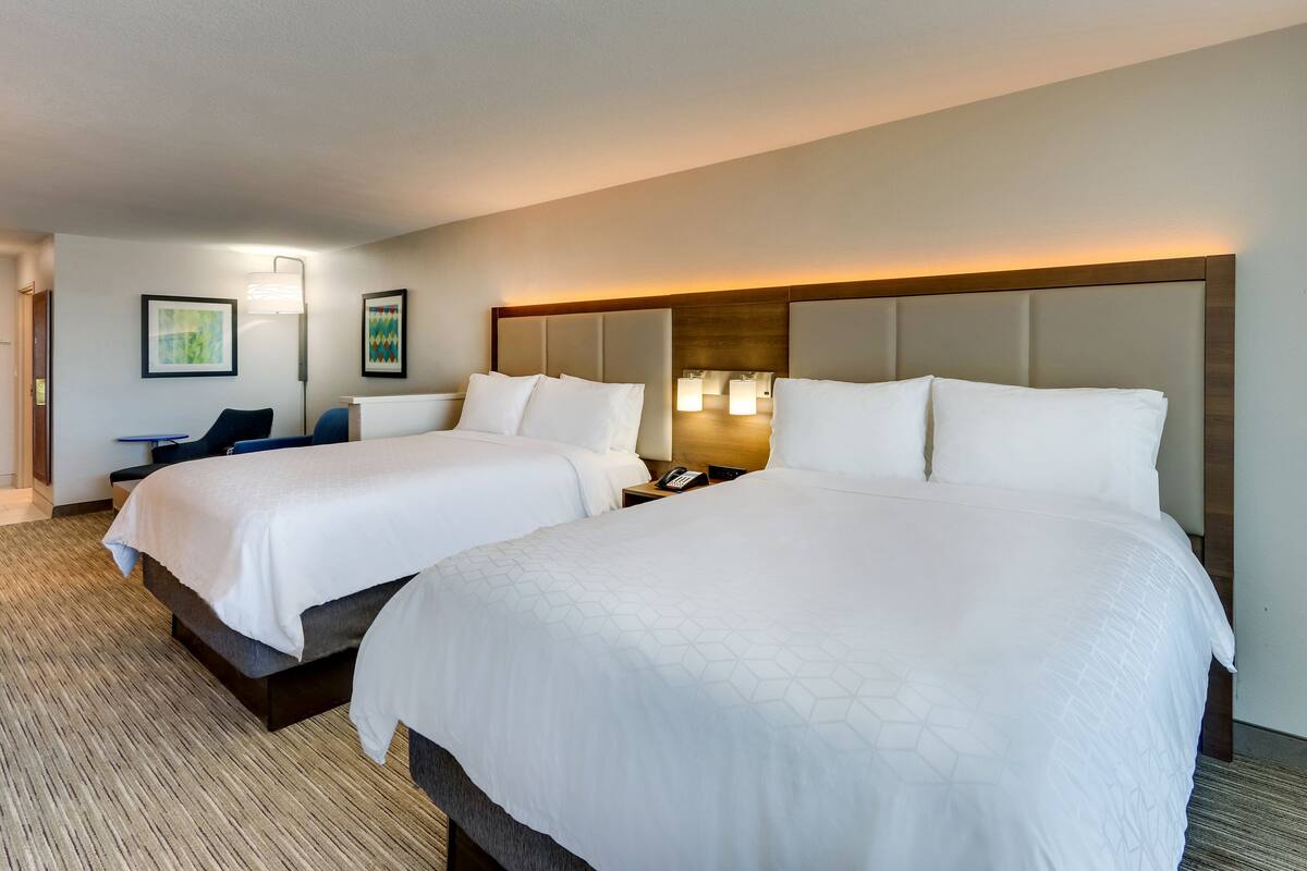 A hotel room with two beds, a desk, and a chair.