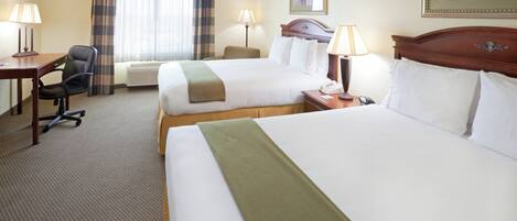 A hotel room with two beds, a desk, a chair, and a window with curtains.