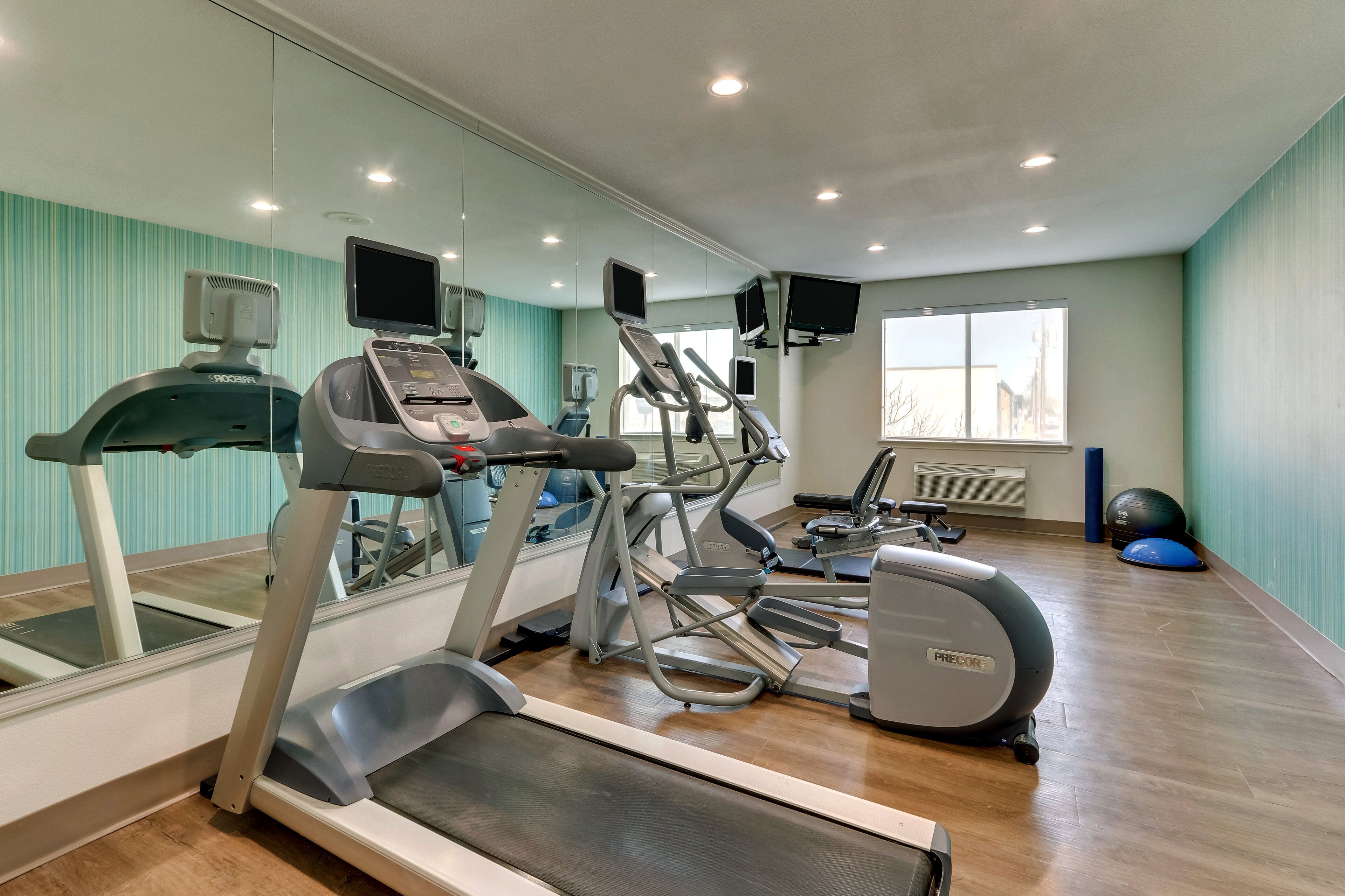 A gym with treadmills, elliptical machines, and exercise balls.