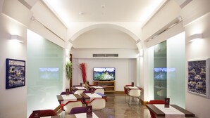 Un salón de conferencias con mesas, sillas, una pantalla grande y paredes de vidrio.