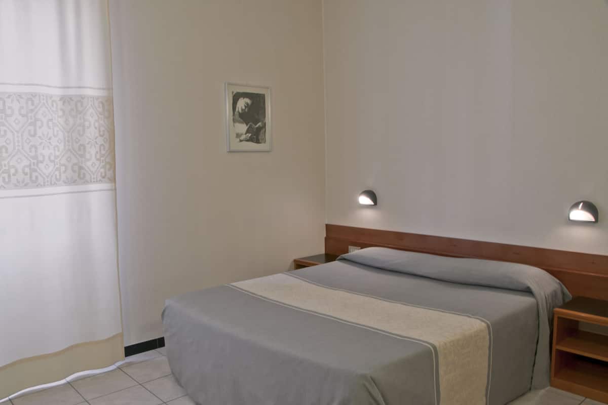 A simple, clean room with a bed, bedside tables, and a wall-mounted picture.