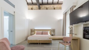 Un dormitorio con cama, mesitas de noche, televisor y espacio de escritorio.