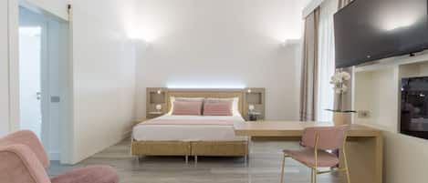 Une chambre à coucher comprenant un lit, des tables de chevet, un téléviseur et un espace bureau.